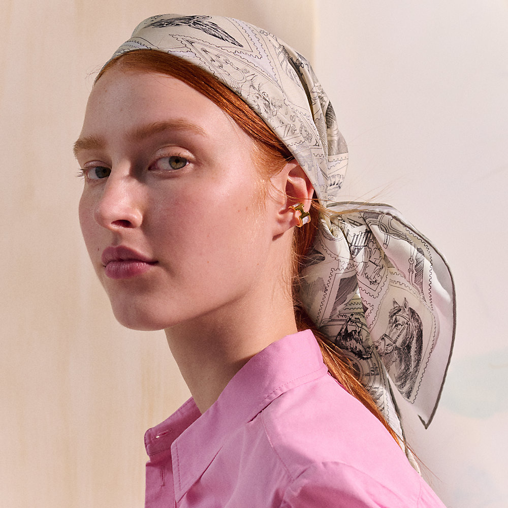 Model wearing a grey patterned Hermès Carré 90 as a headscarf.